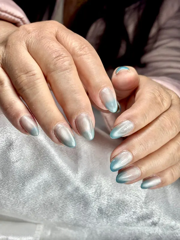 Uñas almendradas en tono perla con degradado azul en la punta