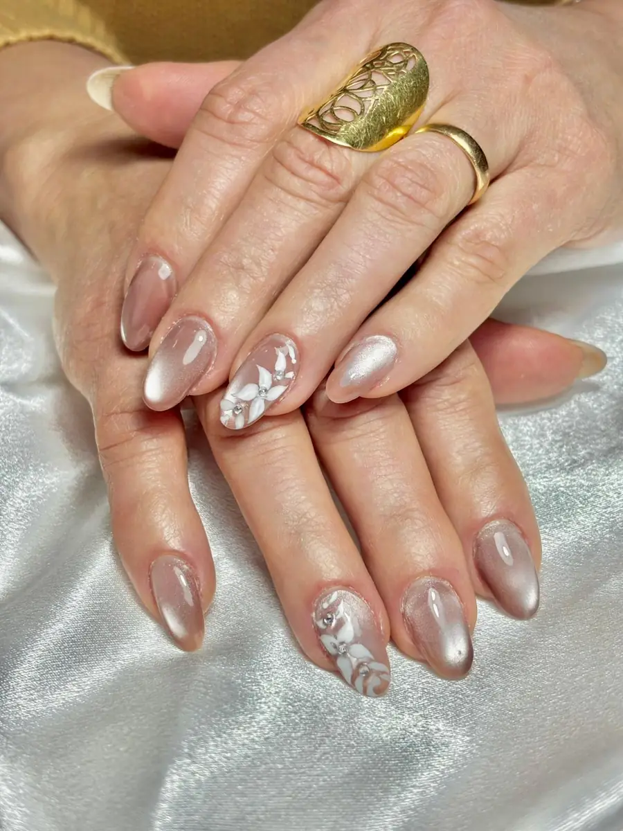 Uñas nude con brillo perlado y flores blancas pintadas, trabajo de manicura en Bonikas Sabadell